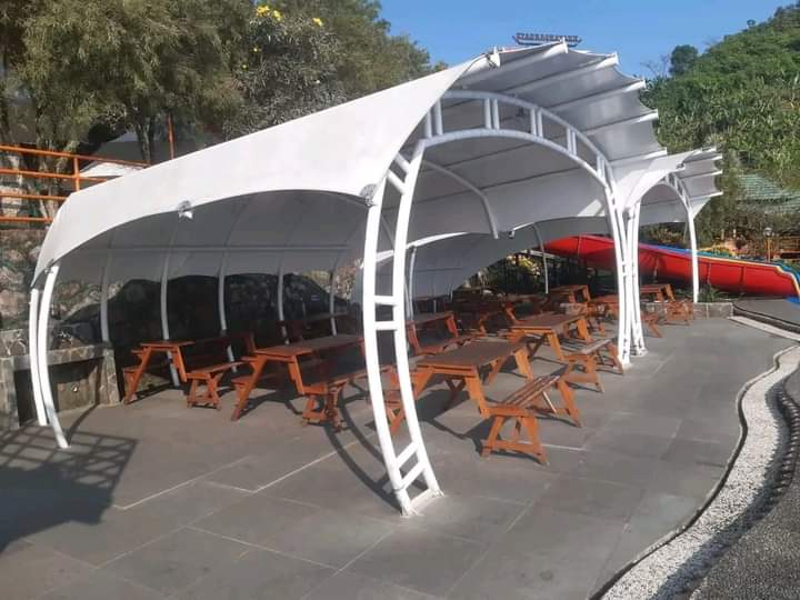 Tenda membran putih artistik terpasang di area outdoor cafe